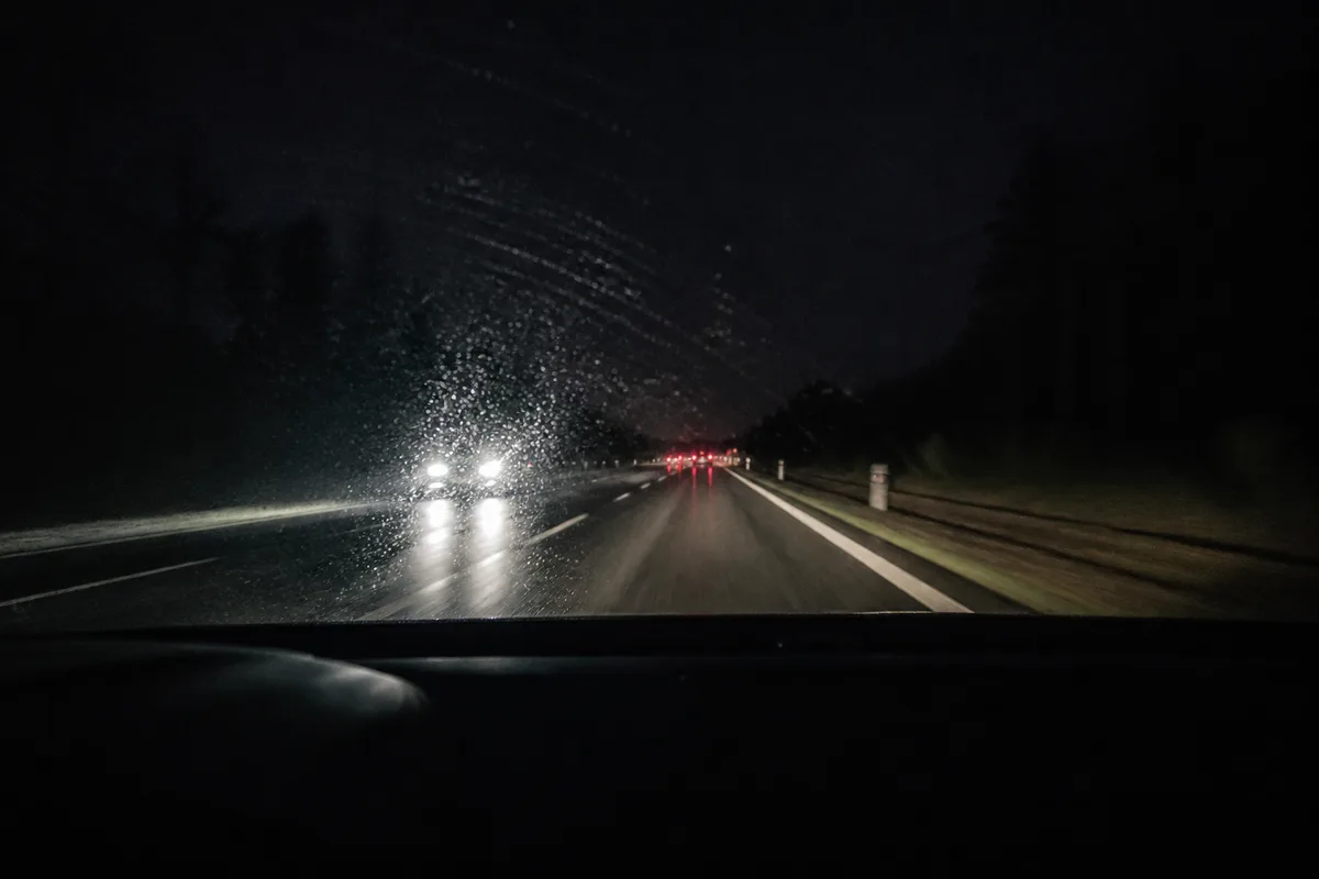 Pare-brise vu de l&rsquo;intérieur avec les halos lumineux des véhicules venant en face